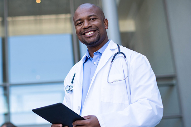 Portrait of smiling doctor standing with digital tablet